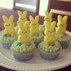 some cupcakes with peeps on them sitting on a plate