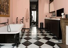 a bathroom with black and white checkered flooring, pink walls and an old fashioned bathtub