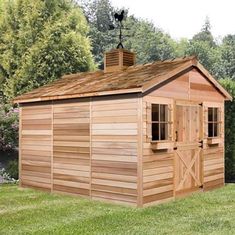 a large wooden shed sitting on top of a lush green field