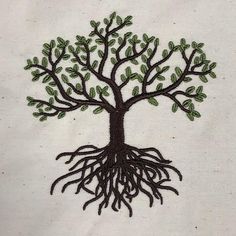 a tree with green leaves and roots is embroidered onto a white fabric material, which has been stitched on to it