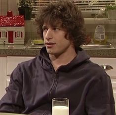 a young man sitting at a table with a glass of milk in front of him