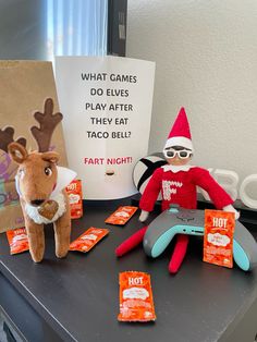 two elfs are sitting on a table next to an electronic game controller and some candy