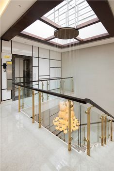 an indoor staircase with glass railing and chandelier