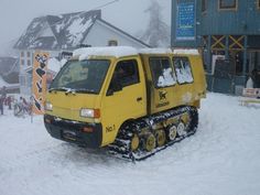 a snowplow is parked in the middle of a snowy area with people standing around