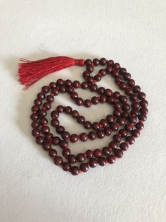 The beads of this mala are 100 % authentic and original. Tibetan / Mahayana style mala. Can be worn as a necklace or a wrap bracelet. Mala is made in traditional way with knots between the beads. Total beads 108+1 There are two kinds of sandalwood Red ( Rakta ) and white (Shweta). Rosaries of red sandalwood are useful for propitiating the goddess whereas white are useful for the gods. Red sandalwood is the symbol of Brahma and blessed by Lakshmi. It enlightens the super consciousness, provides i Super Consciousness, Red Sandalwood, Prayer Beads, Yoga Meditation, Consciousness, Dark Red, Wrap Bracelet, Meditation, Beaded Necklace