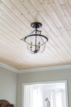 a light fixture hanging from the ceiling in a room with white walls and wood paneling