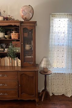 a book shelf with books and other items on top of it next to a window