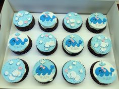 there are twelve cupcakes in the box with blue frosting and elephants on them