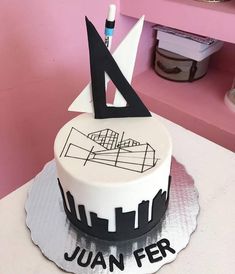 a white and black cake sitting on top of a table next to a pink wall