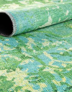 a green and blue rug with an ornate design on it's side, laying on the floor