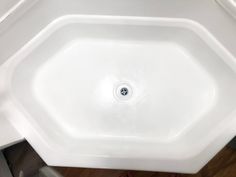 the corner of a bathroom sink with a drain running through it's center hole