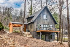 a house in the woods with a covered porch and stairs leading up to it's second story