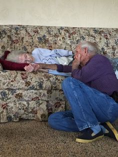 an older man and woman sitting on a couch