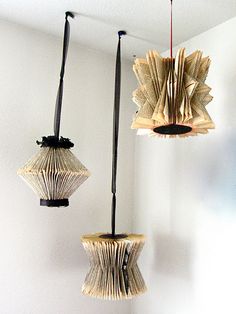 two lamps made out of book pages hanging from the ceiling in a room with white walls