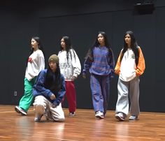 several young people standing on a wooden floor in front of a black wall and wearing white sweatshirts