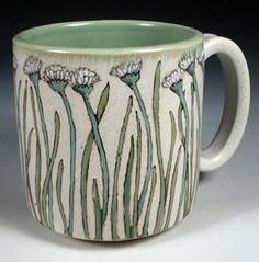 a white and green coffee cup with flowers on it