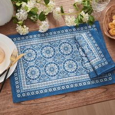 a blue placemat on a wooden table with plates and utensils next to it