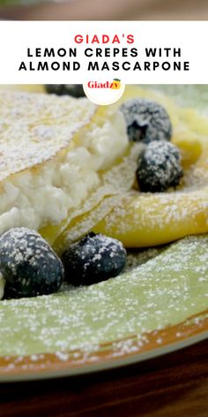 a plate topped with lemon and blueberries covered in powdered sugar on top of a wooden table