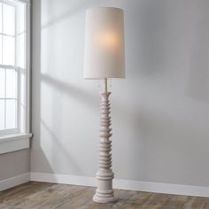 a lamp that is on top of a wooden floor next to a window in a room