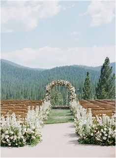 an outdoor ceremony setup with white flowers and greenery