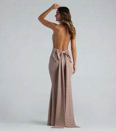 the back of a woman wearing a nude colored dress with a bow at the waist