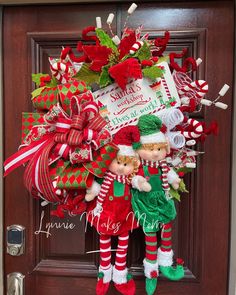 a christmas wreath with two elfs hanging on the front door