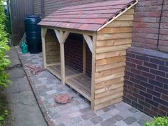 a dog house built into the side of a brick building with a wooden roof and door