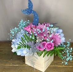 a wooden box filled with purple and blue flowers on top of a wood table next to a number 3 sign