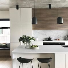 two stools sit at the kitchen island in this white and wood - paneled kitchen