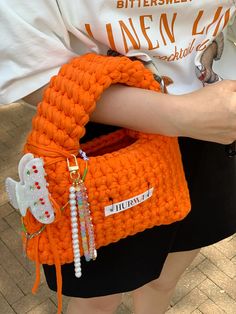 an orange purse is being held by a woman's arm with beads on it