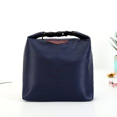 a blue bag sitting on top of a white table next to a potted plant