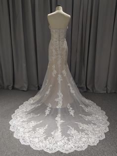 the back of a wedding dress on a mannequin with white lace and flowers