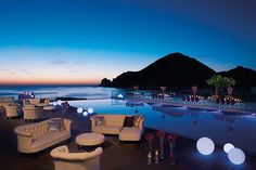 an outdoor seating area next to the ocean at night