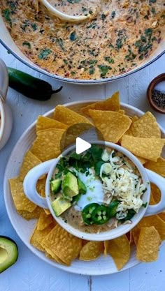 a bowl of soup with tortilla chips and avocado on the side