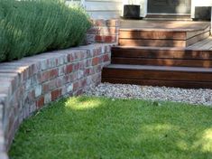 a brick wall and steps in front of a house with green grass on the ground