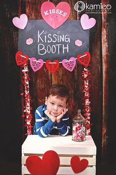 a little boy sitting on top of a table with candy in front of his face