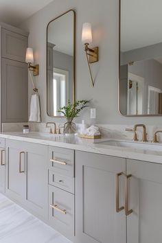 a bathroom with two sinks, mirrors and lights on the wall above them is shown