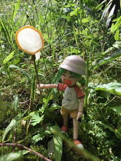 a doll is standing in the grass with a frisbee on its head and wearing a hat