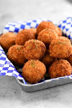 a tin filled with fried food sitting on top of a checkered cloth covered table