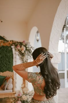 a woman with long hair and tattoos on her arm standing in front of a fireplace