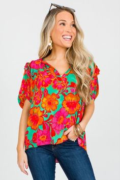 Bold and bright floral print top with sweet ruffled shoulders and ties at the split neckline. Green Tie Neck Top For Summer, Spring Rayon Top With Split Neck, Vibrant Green Blouse For Spring, Floral Print Rayon Tops, Green Floral Print Blouse With Ruffle Sleeves, Green Ruffle Sleeve Top With Floral Print, Summer Floral Print Split Neck Blouse, Green Top With Ruffle Sleeves And Floral Print, Floral Print Patterned Rayon Tops