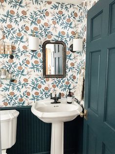 a white sink sitting under a bathroom mirror next to a toilet and a blue door