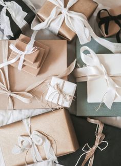 many wrapped presents are laying on the bed with white and black ribbons around them,