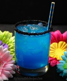 a blue drink sitting on top of a table next to flowers