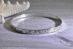 "This gorgeous sterling silver bangle bracelet is hand stamped with \"Faith, Hope, Love.\" I decorated it with lots of flowers, leaves, and vines. Bangle is approximately 1/4\" wide and 1.5mm thick. Want to say something else? Just write me a note in the message to seller box at checkout. Up to 100 characters and spaces please. If you need more, please contact me first. To find your size fold your thumb over your palm as if you were putting on a bangle and measure the widest part of your hand, a Stamped Sterling Silver Bangle For Wedding, Sterling Silver Stamped Bangle For Wedding, Wedding Sterling Silver Stamped Bangle, Silver Bangle Bracelet, Sterling Silver Bangle Bracelets, Sterling Silver Bangle, Faith Hope Love, Silver Bangle Bracelets, Sterling Silver Bangles