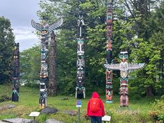 a person standing in front of some totem poles