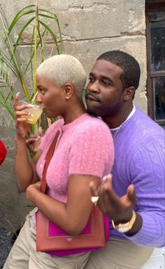 a man and woman sitting next to each other with drinks in their hands on the ground