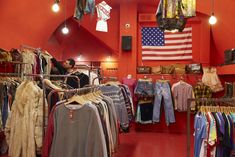 a clothing store filled with lots of clothes and hanging items on racks in front of an american flag