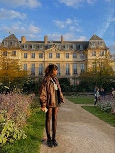 a woman standing on a path in front of a large building with lots of windows