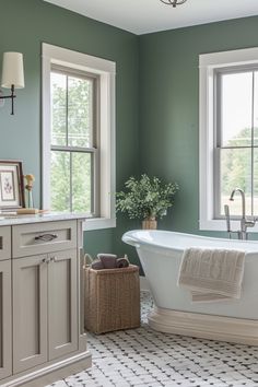 a bathroom with green walls and white bathtub next to two windows in the corner